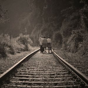 Three people walking along the railway track.